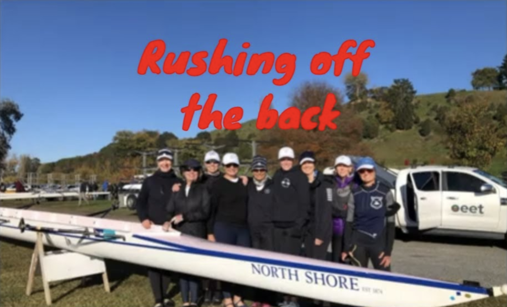 9 women with a rowing shell in a park.